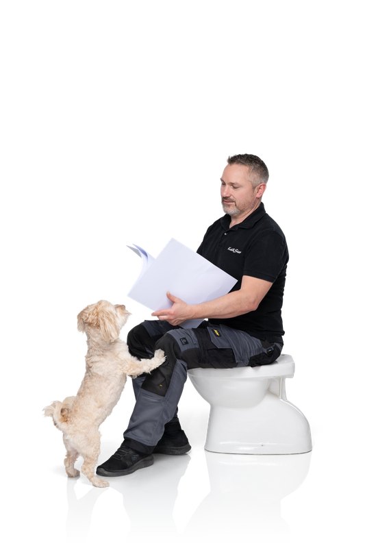 Andreas Neuenschwander sitzt mit Papieren auf einem WC, Bürohund Sämy steht mit den Vorderpfoten an seinem Bein