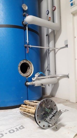 Heizelement eines Boilers mit Kalkablagerungen, ausgebaut auf einer Unterlage