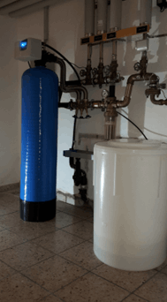Enthärtungsanlage mit blauem Druckbehälter und weissem Salztank im Technikraum