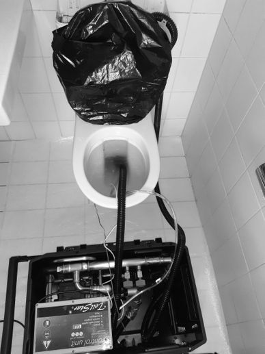 ToilStar-Reinigungsgerät mit Schläuchen neben einer WC-Anlage im Einsatz, der Boden ist mit Vlies geschützt